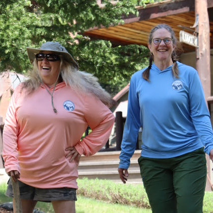 Two women walking outdoors with a wooden cabin in the background