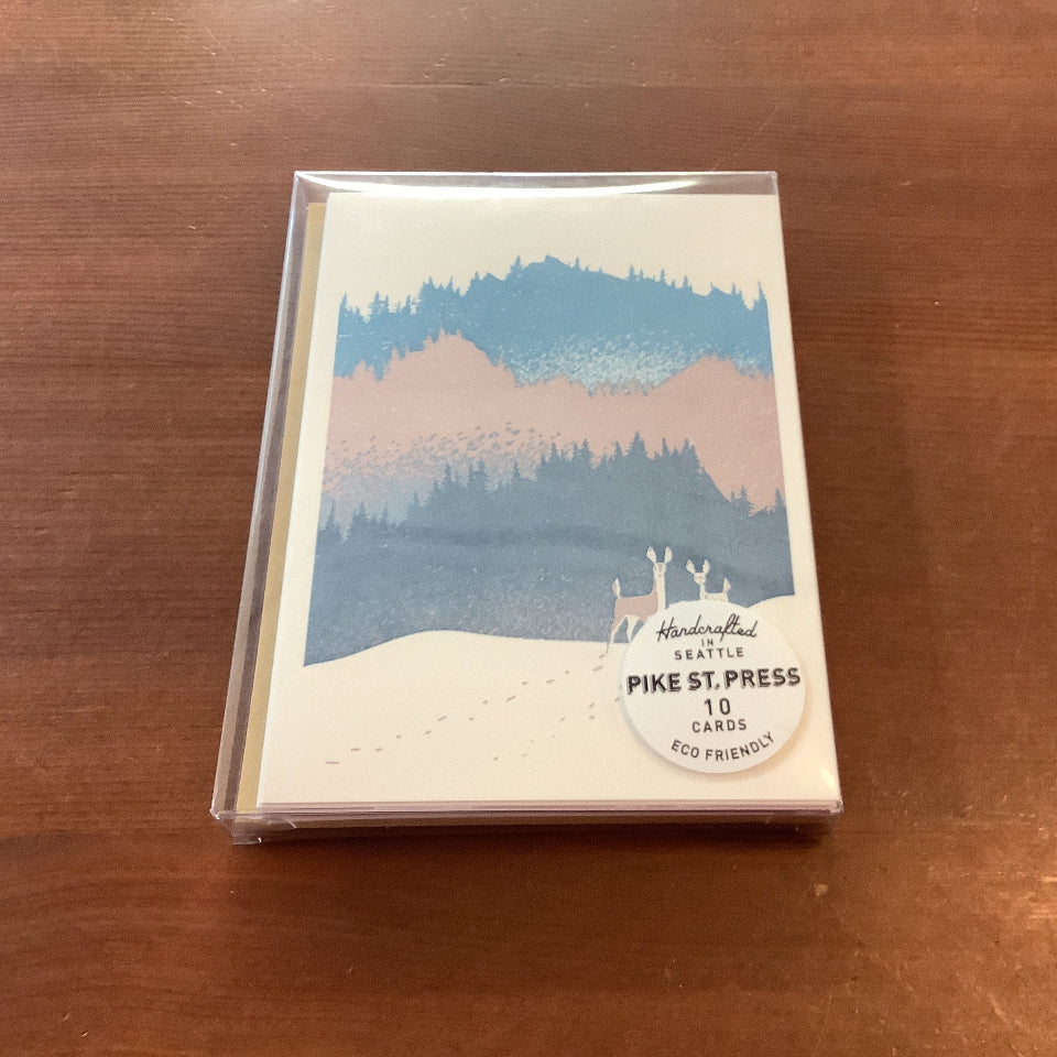 A boxed card set from Pike St. Press titled 'Heidi Kuchler Seattle' featuring a winter mountain landscape illustration, placed on a wooden tabletop.