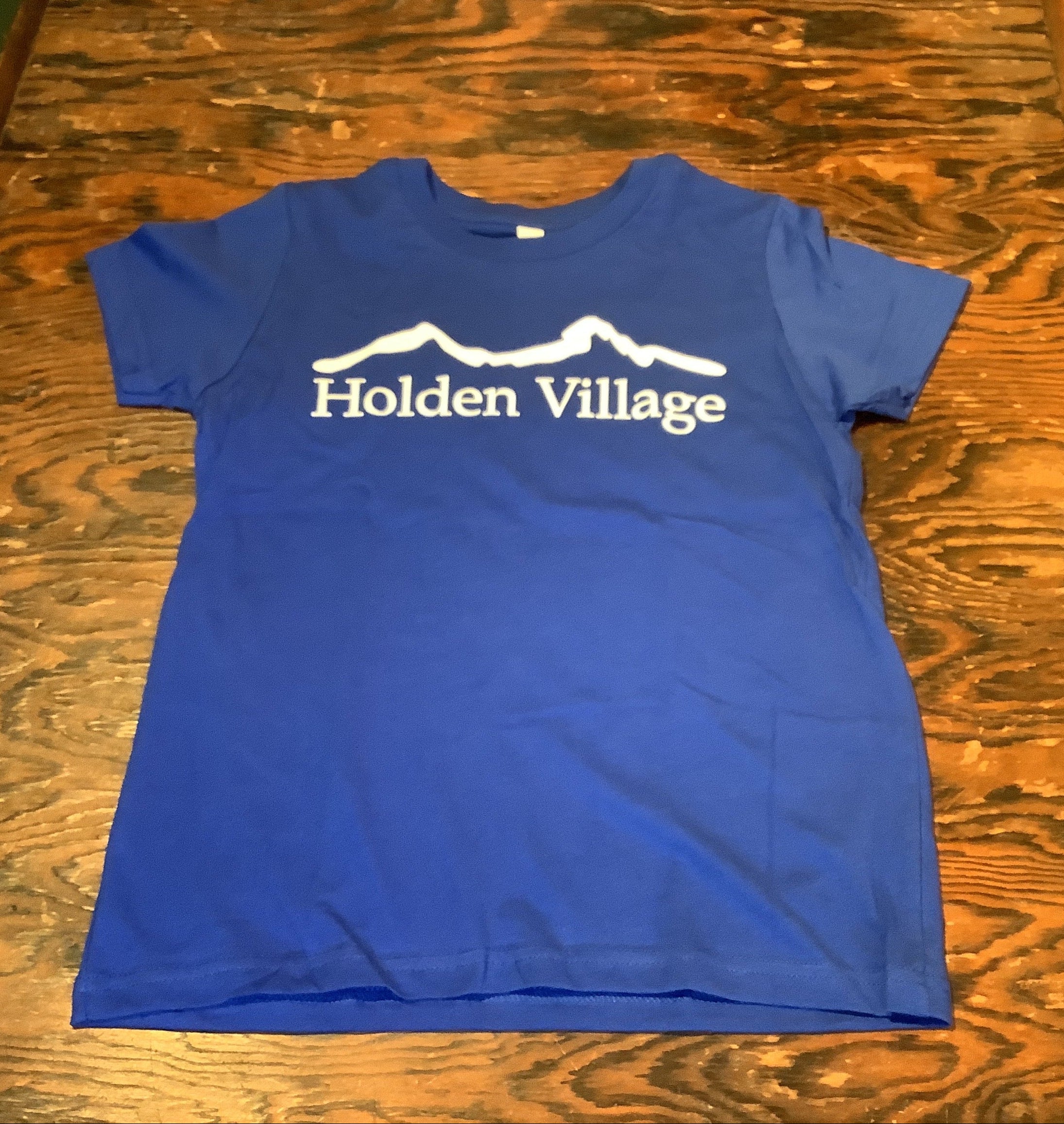 A royal blue short-sleeve t-shirt with 'Holden Village' and a mountain graphic printed in white on the front.