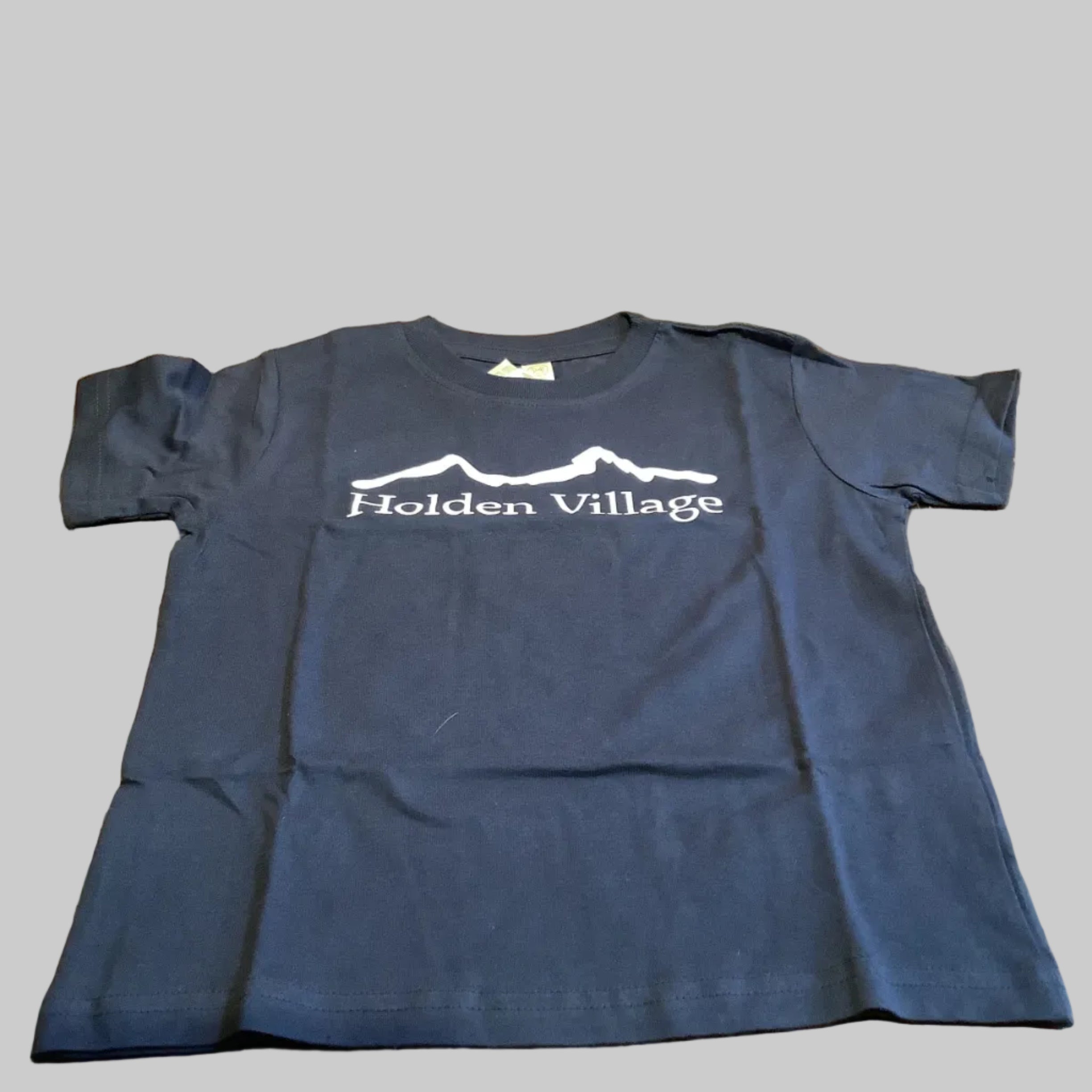 Folded navy blue t-shirt with 'Hollen Village' logo on a wooden surface