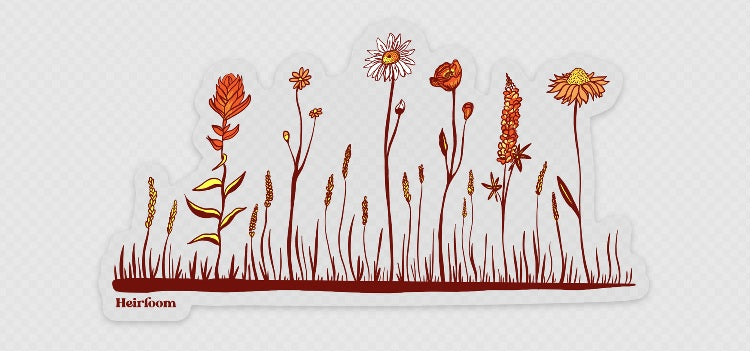 A die-cut sticker featuring a stylized illustration of wildflowers and grass in warm orange, red, and yellow tones on a white background, with the brand name 'Heirloom' printed at the bottom left.