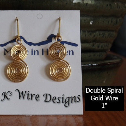 Gold spiral wire earrings on a K3 Wire Designs card with a blurred background