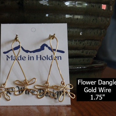 Gold wire flower dangle earrings on a 'Made in Holden' card with a blurred background.