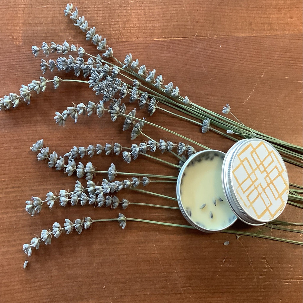 Balm in a tin with a decorative lid on a wooden surface with lavender flowers.