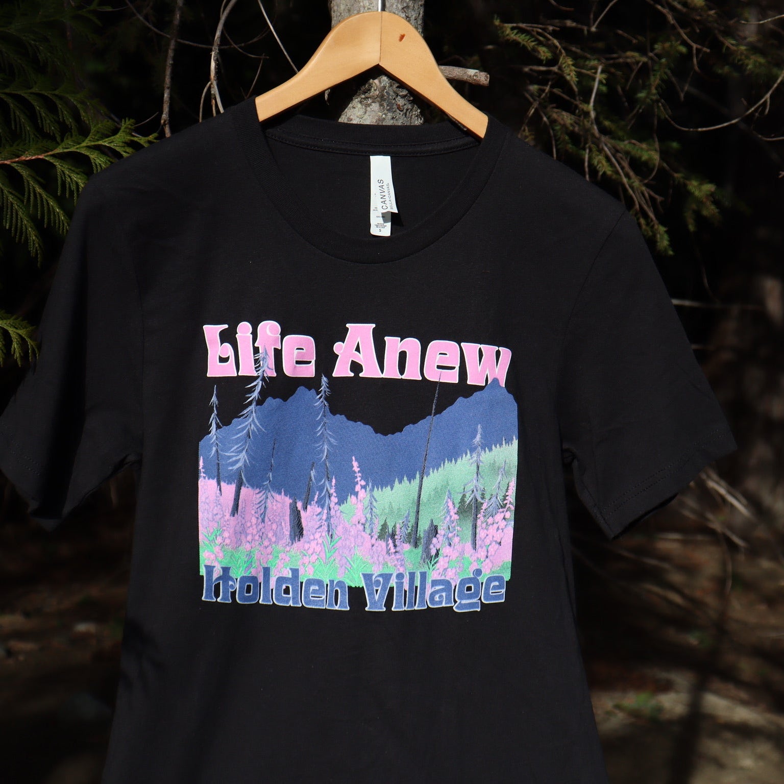 Black t-shirt with 'Life Anew' and mountain graphic on a hanger against a dark background