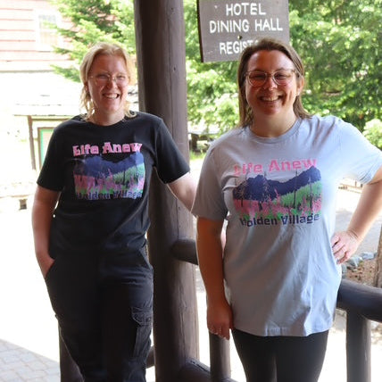 Two people wearing t-shirts with 'Life Awa' text on a wooden deck.