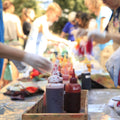 People tie dying at an outdoor event with color bottles on a table.